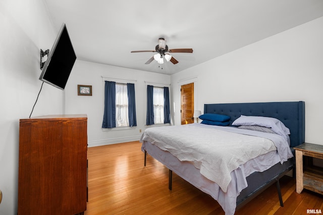 bedroom with ceiling fan, baseboards, and hardwood / wood-style flooring