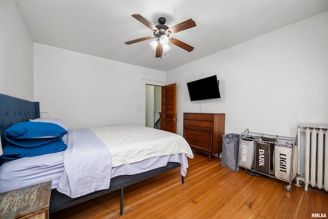 bedroom with a ceiling fan, hardwood / wood-style floors, and radiator heating unit