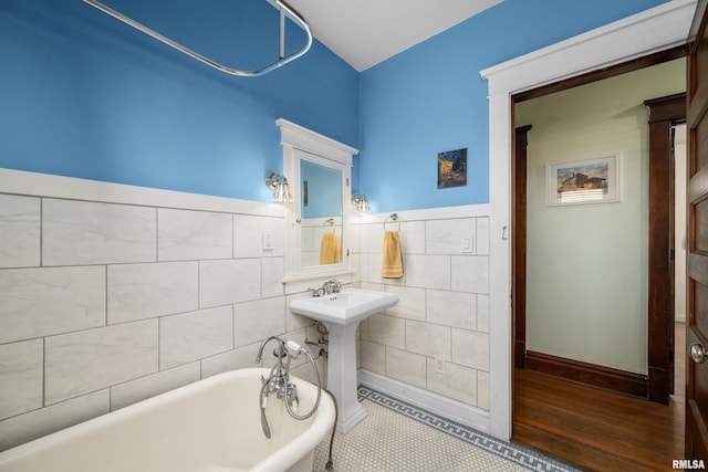 full bath with a sink, tile walls, and a freestanding bath