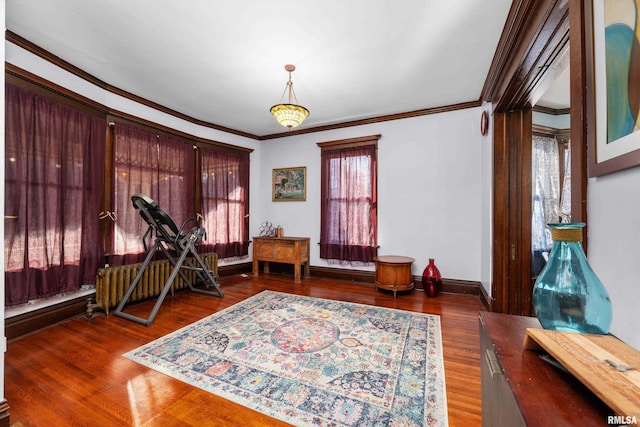 sitting room featuring baseboards, wood finished floors, and crown molding