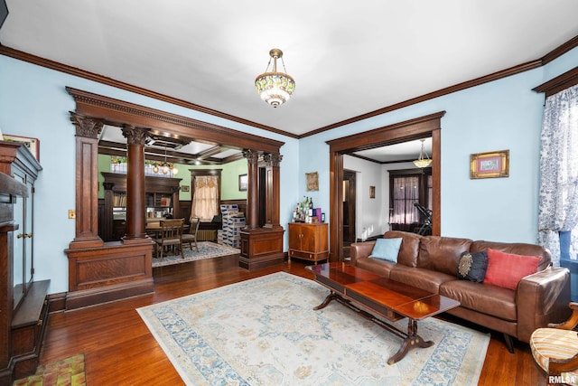 living room with a notable chandelier, wood finished floors, crown molding, and ornate columns