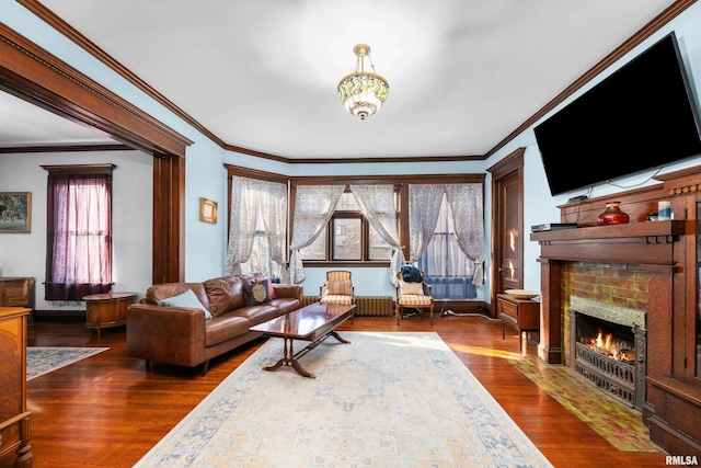 living area featuring dark wood-type flooring, a brick fireplace, and crown molding