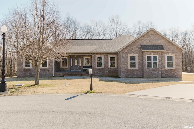 ranch-style house with a front lawn, brick siding, and roof with shingles