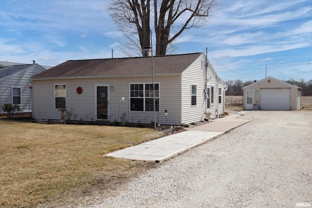 view of front facade featuring a detached garage, a front lawn, roof with shingles, an outdoor structure, and driveway