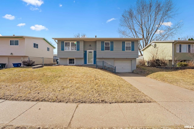 split foyer home with concrete driveway, a garage, and a front yard