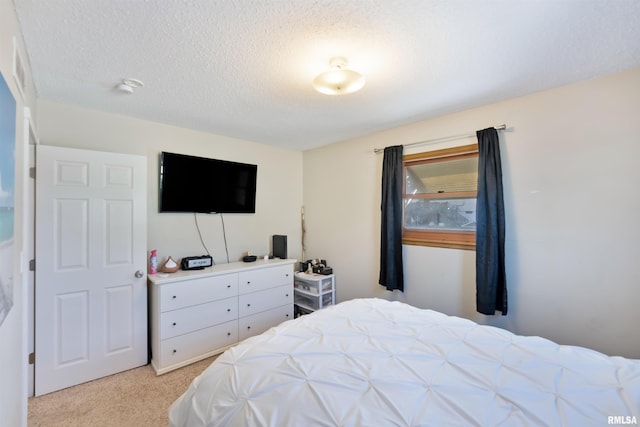 bedroom featuring light carpet and a textured ceiling