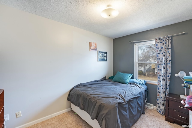 bedroom with light colored carpet, a textured ceiling, and baseboards