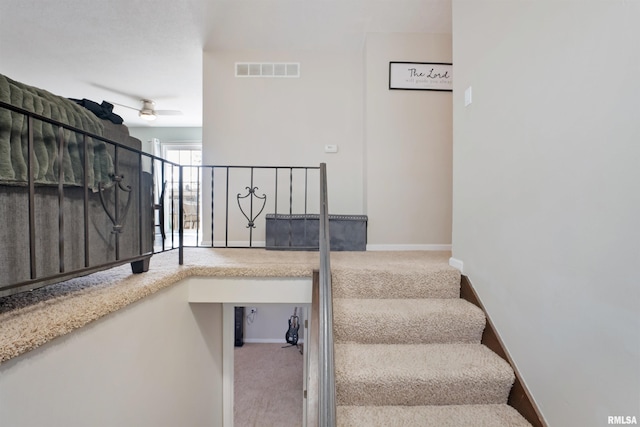 staircase with visible vents, a ceiling fan, baseboards, and carpet floors