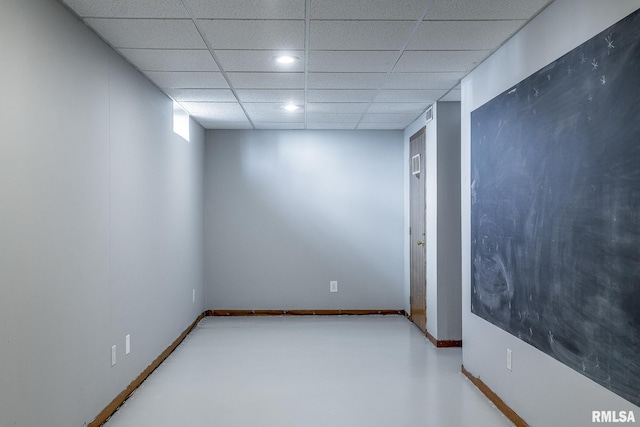 unfurnished room featuring a paneled ceiling, baseboards, and finished concrete floors