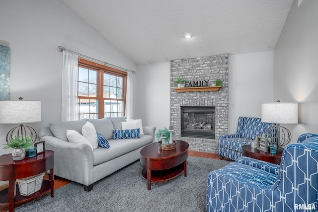 living area featuring a brick fireplace, a textured ceiling, lofted ceiling, and wood finished floors