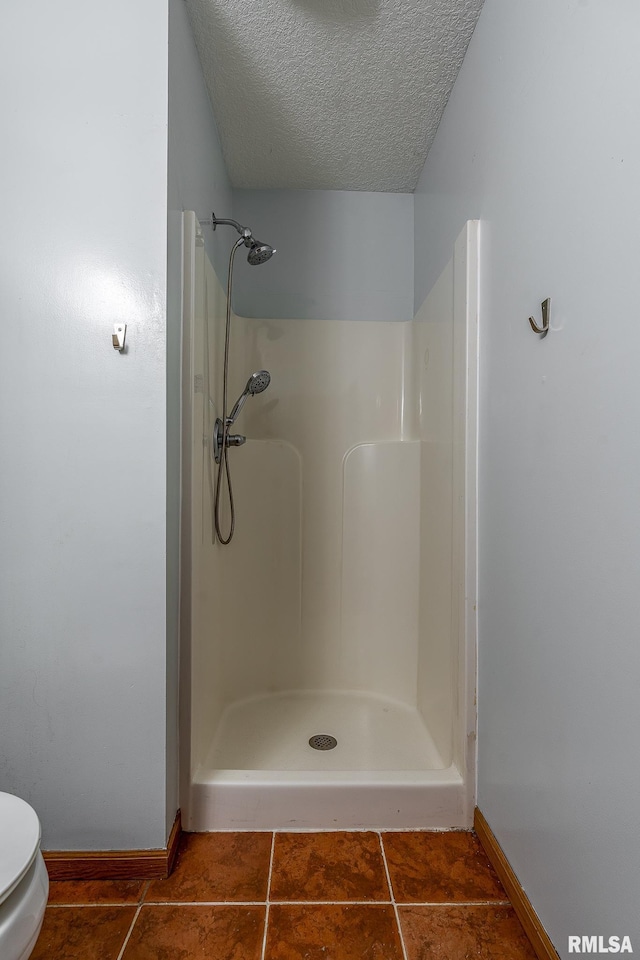 full bath with tile patterned floors, toilet, a stall shower, and a textured ceiling