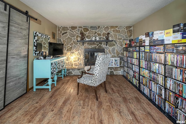 living area with a barn door, a textured ceiling, wood finished floors, and bookshelves