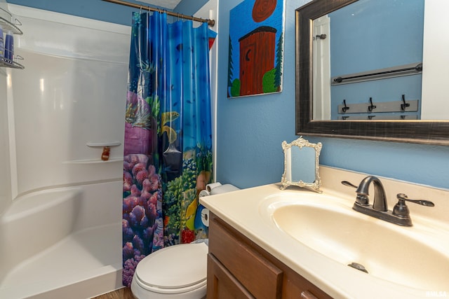 full bath with vanity, toilet, a textured wall, and a stall shower