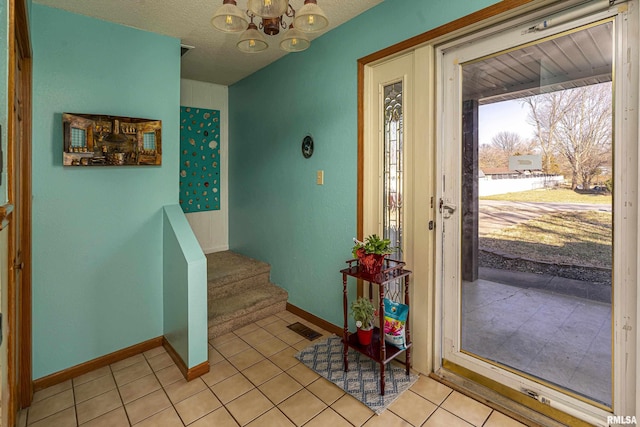 foyer with stairway, light tile patterned floors, baseboards, a textured ceiling, and a chandelier