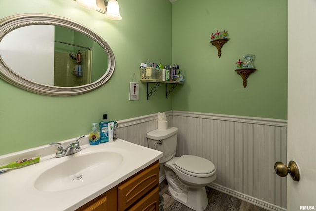 bathroom with wainscoting, toilet, vanity, and wood finished floors