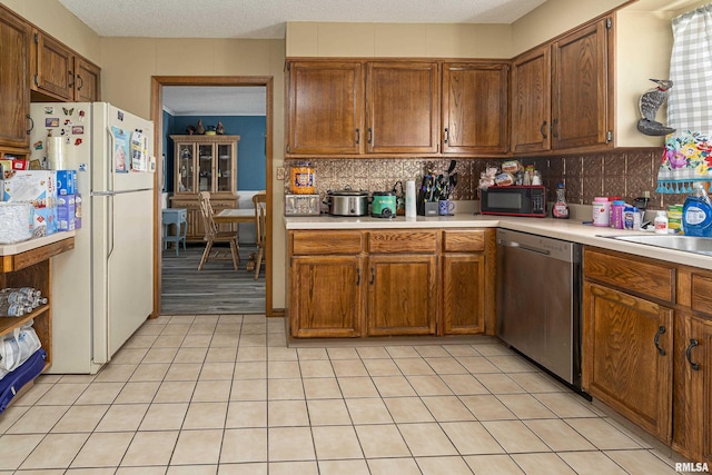 kitchen featuring freestanding refrigerator, decorative backsplash, light countertops, black microwave, and stainless steel dishwasher