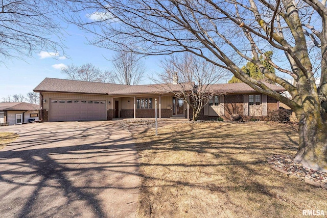 ranch-style home featuring brick siding, covered porch, a chimney, driveway, and an attached garage