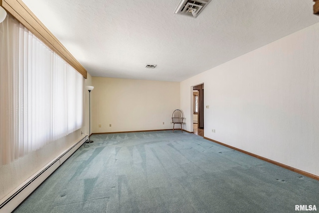 carpeted empty room with visible vents, a textured ceiling, a baseboard heating unit, and baseboards