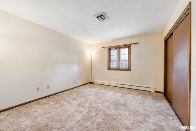 unfurnished bedroom with visible vents, carpet flooring, a baseboard heating unit, and baseboards