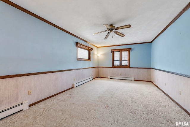 carpeted spare room with a baseboard heating unit, a ceiling fan, a wainscoted wall, and baseboard heating