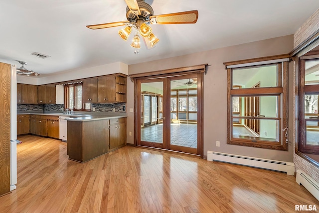 kitchen featuring light wood finished floors, baseboard heating, french doors, and a peninsula