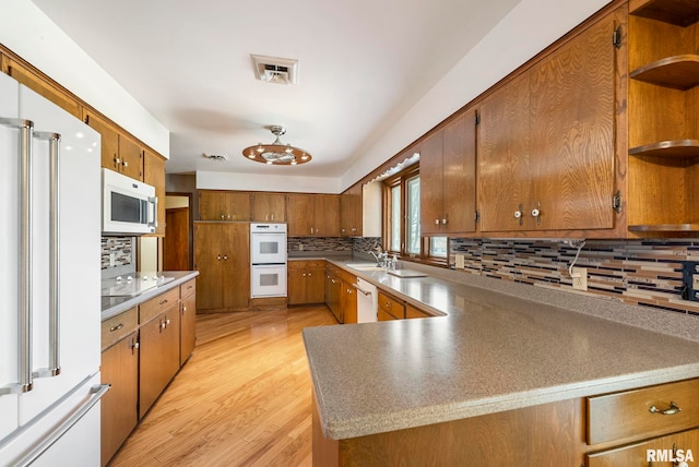 kitchen with decorative backsplash, white appliances, brown cabinetry, and open shelves