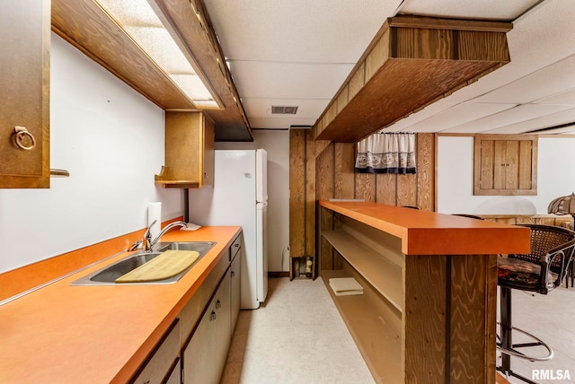 kitchen featuring visible vents, a sink, light countertops, a kitchen breakfast bar, and open shelves