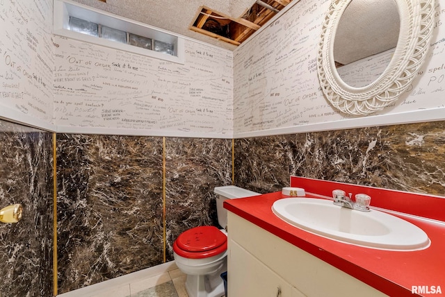 bathroom with tile patterned floors, vanity, toilet, and tile walls