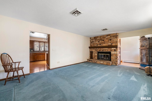 unfurnished living room with visible vents, carpet floors, baseboard heating, and a fireplace