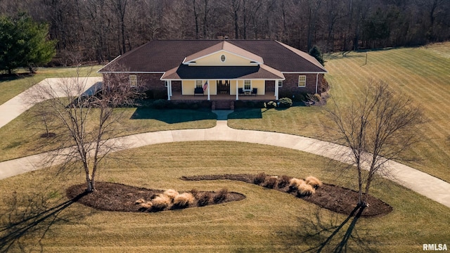 view of front of house featuring a forest view, a porch, and a front yard