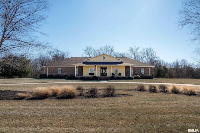 view of front of house with brick siding, a porch, and a front lawn