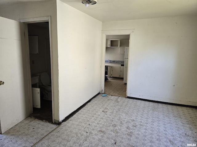 unfurnished bedroom with tile patterned floors, freestanding refrigerator, and baseboards