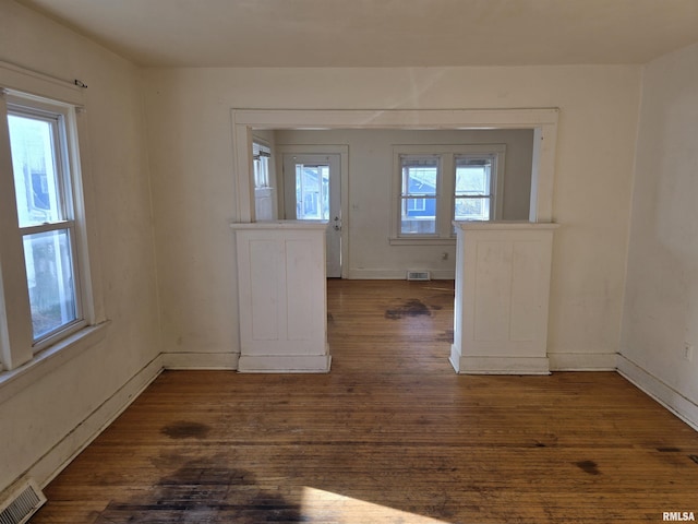 empty room with visible vents, baseboards, and dark wood-type flooring