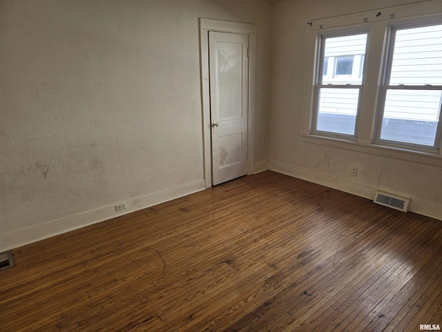 empty room with visible vents, baseboards, and dark wood-style flooring