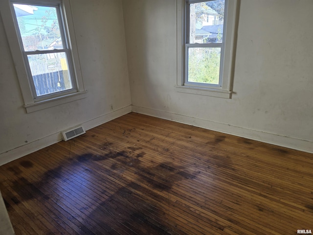 empty room featuring hardwood / wood-style flooring, baseboards, and visible vents