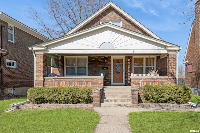 bungalow with a porch, brick siding, and a front yard