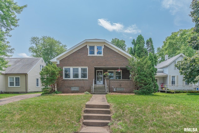 bungalow-style home with a front yard, covered porch, and brick siding