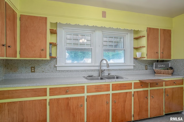 kitchen with open shelves, a sink, light countertops, brown cabinets, and backsplash