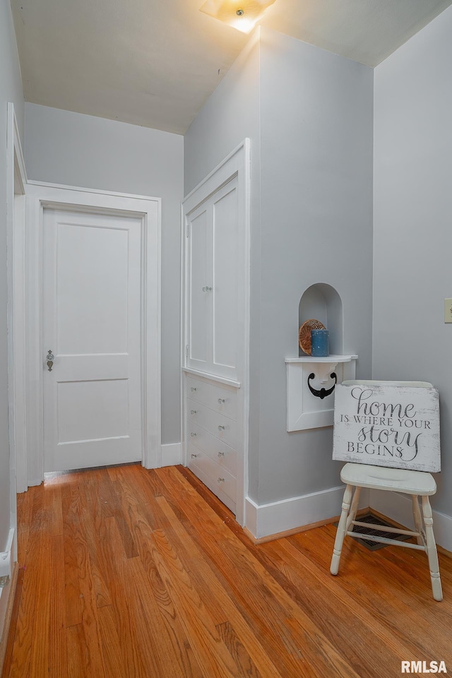 corridor featuring baseboards and light wood finished floors