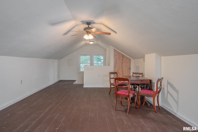 dining space with hardwood / wood-style floors, vaulted ceiling, baseboards, and a textured ceiling