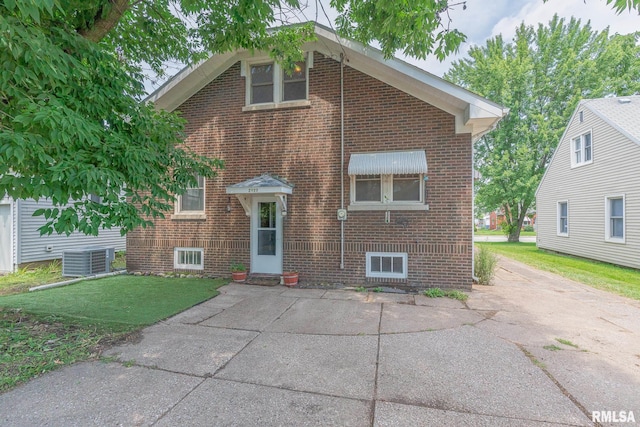 view of front facade with brick siding, central AC, and a front yard