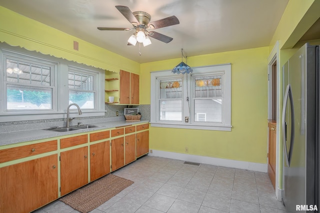 kitchen with light countertops, freestanding refrigerator, baseboards, and a sink