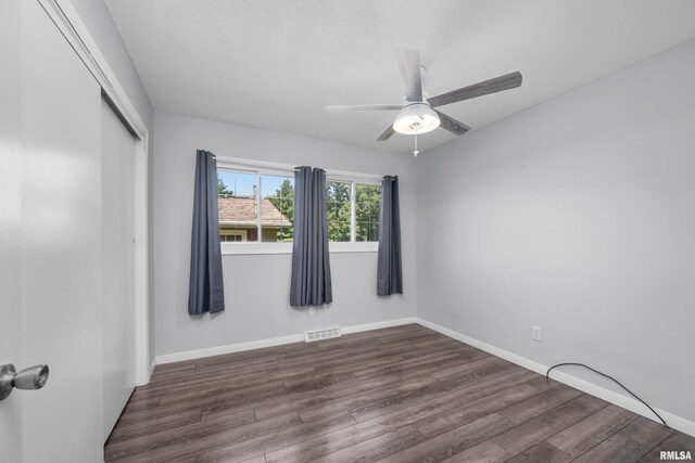 spare room with dark wood-style floors, visible vents, a ceiling fan, and baseboards