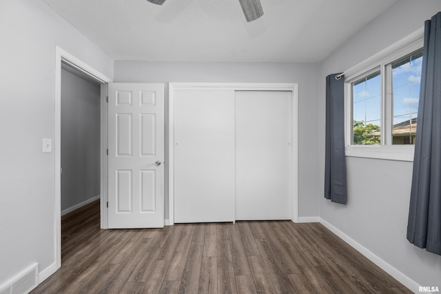 unfurnished bedroom with wood finished floors, visible vents, baseboards, ceiling fan, and a closet