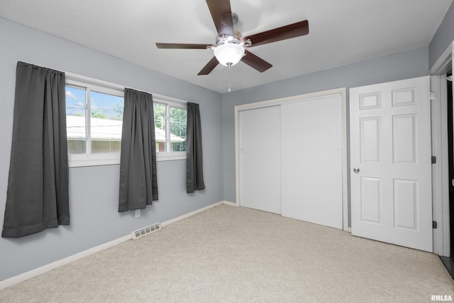 unfurnished bedroom with a ceiling fan, carpet, visible vents, baseboards, and a closet