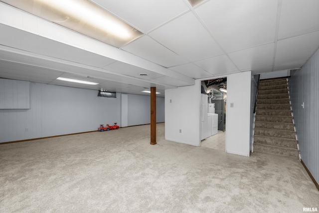 finished basement featuring stairs, carpet, and a paneled ceiling