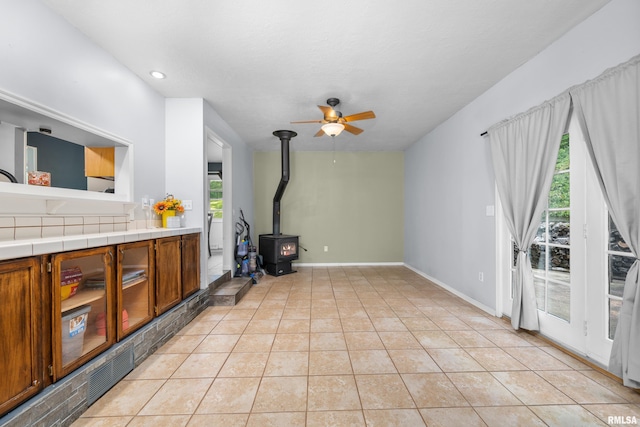 living area featuring ceiling fan, baseboards, light tile patterned floors, recessed lighting, and a wood stove