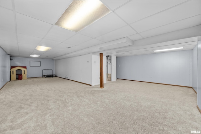 finished below grade area featuring baseboards, a paneled ceiling, and carpet floors