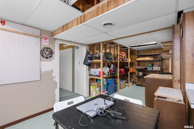 basement featuring baseboards, visible vents, and a drop ceiling