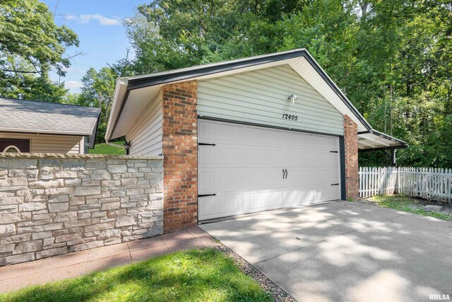 garage with concrete driveway and fence